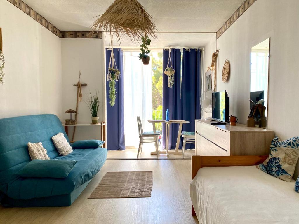 a living room with a blue couch and a tv at Échappée Bohème & Lumière in La Grande-Motte