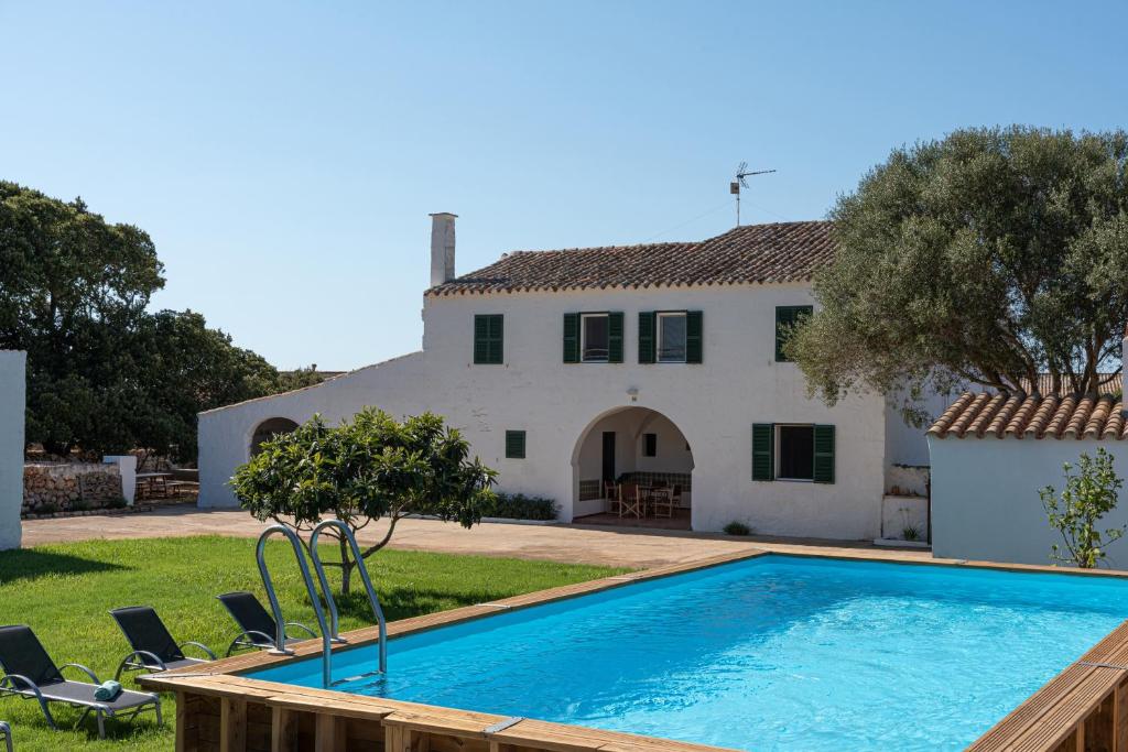 a villa with a swimming pool in front of a house at Son Camaro in Ciutadella