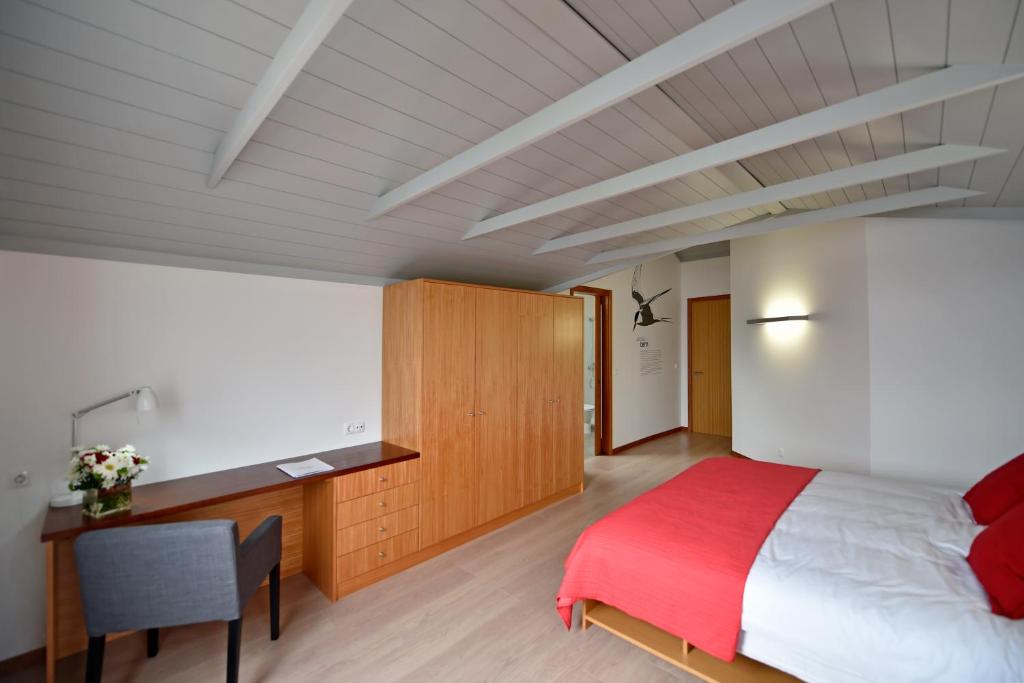 a bedroom with a large bed and a desk at Casa da Baía - Guest House in Horta