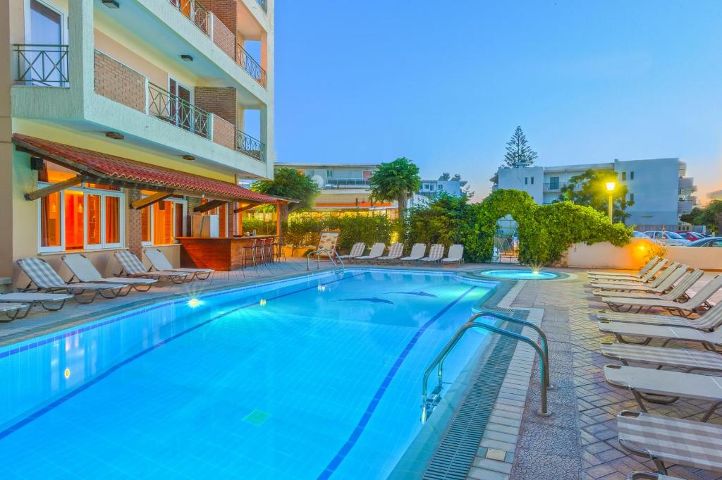 a swimming pool with lounge chairs and a hotel at Pavlos Hotel in Kos Town