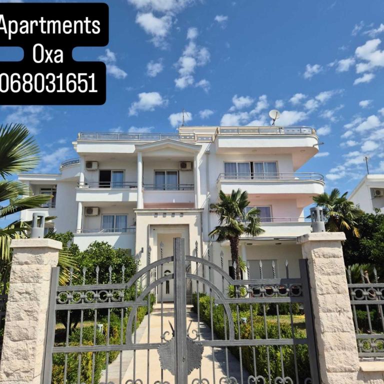 a white house with a gate and palm trees at Apartments Yll in Ulcinj