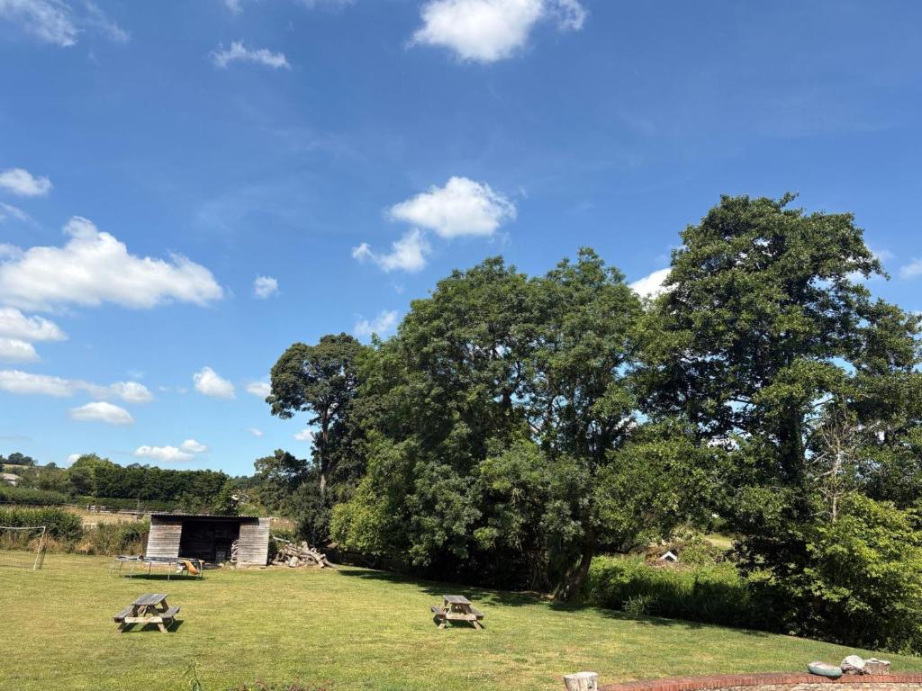 a field with two picnic tables in front of a tree at Portbridge Nest in Chew Magna