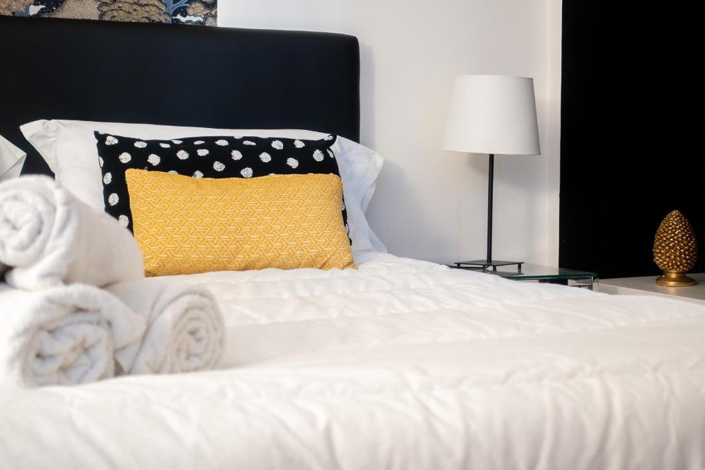 a white bed with a yellow pillow on it at B&B Il Bianco E Il Nero in Siracusa