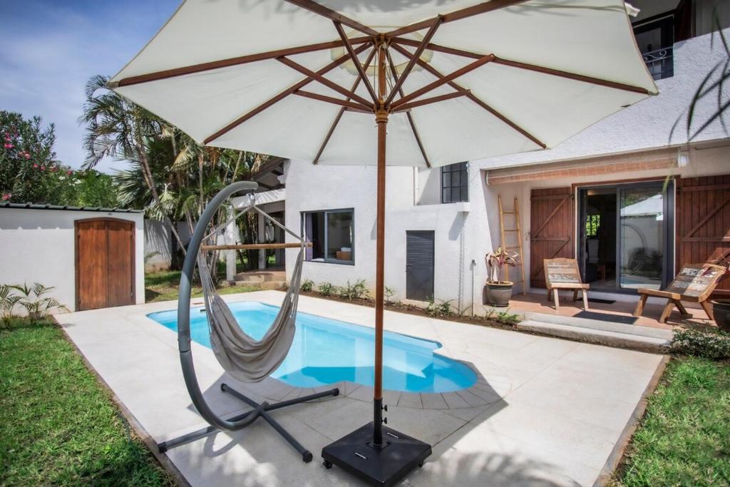 an umbrella and a chair next to a swimming pool at Villa Céleste - 4 Bedrooms in Central Tamarin in Tamarin