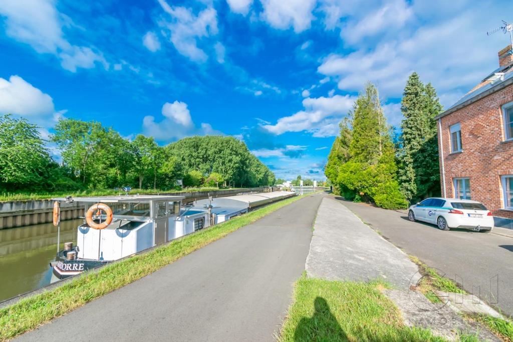 a canal with a boat parked next to a building at Le halage, charmante maison en bordure de rivière 
