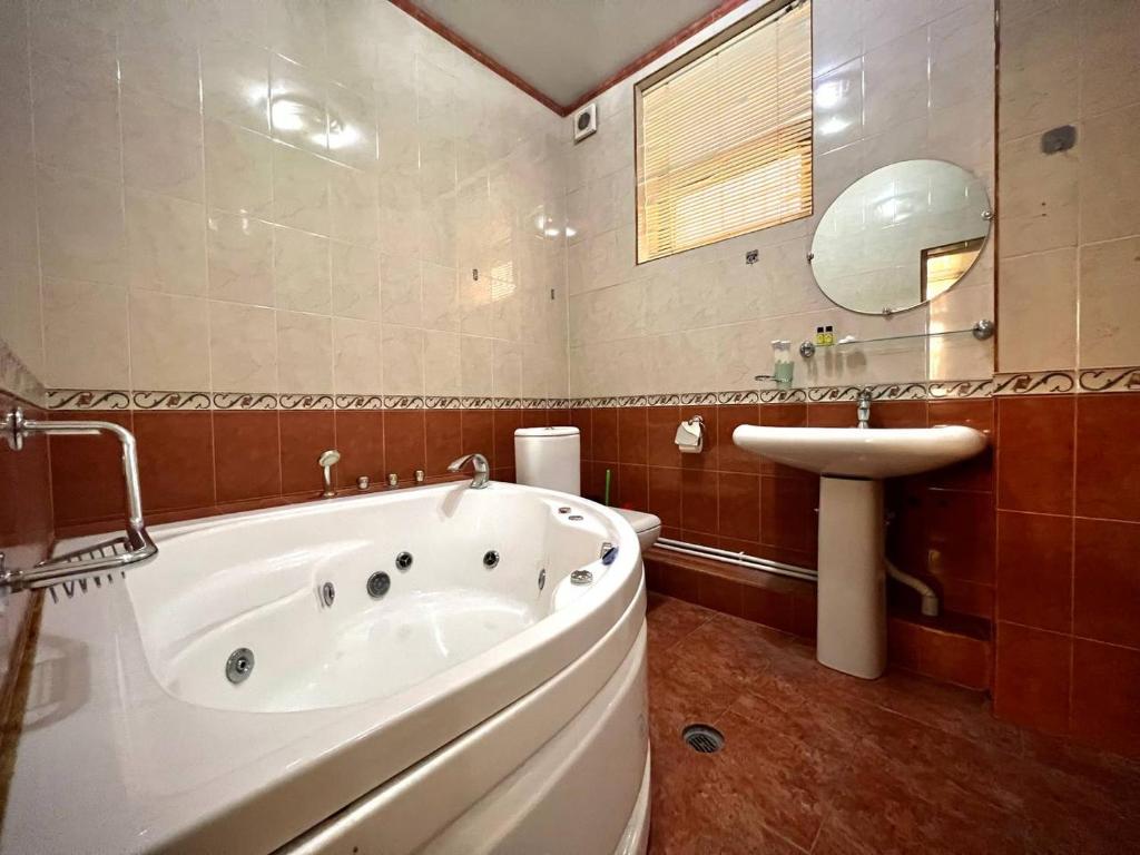 une salle de bain avec une grande baignoire et un lavabo dans l'établissement Green Hotel, à Tachkent