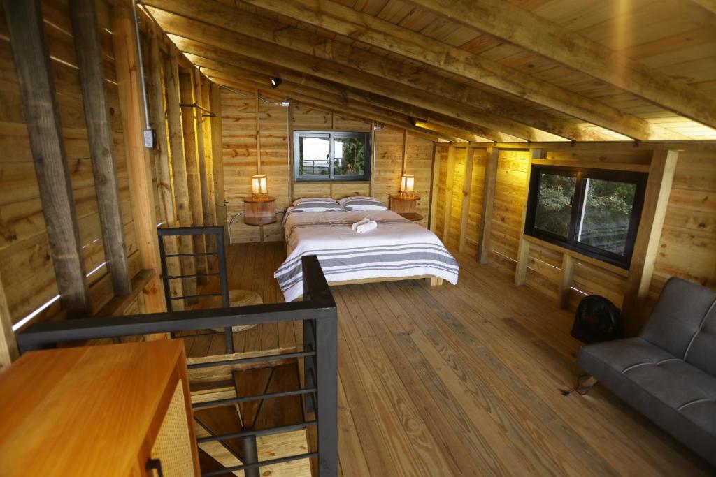 a bedroom in a log cabin with a bed and a couch at Casa Loma, Descansar en la Montaña, 30min STG in La Búcara