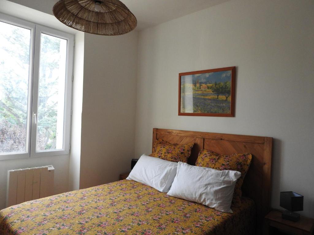 1 dormitorio con 1 cama, ventana y una foto en Le gîte du forgeron, en La Tour-dʼAigues
