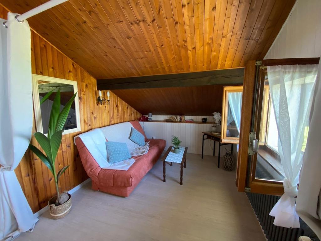 a living room with a red couch and a wooden ceiling at Appartement vue lac in Publier
