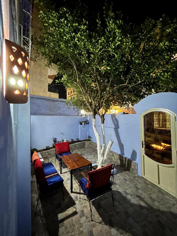 a patio with a table and chairs and a tree at Jb house in Chefchaouen