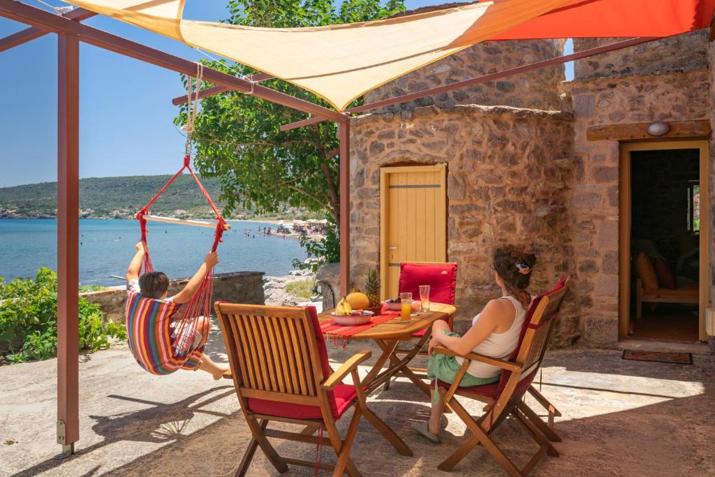 two children playing in hammocks on the patio of a house at Το Καμίνι, πέτρινη κατοικία πάνω στη θάλασσα The Kiln House Kamini, Retreat on the beach in Aspropótamos