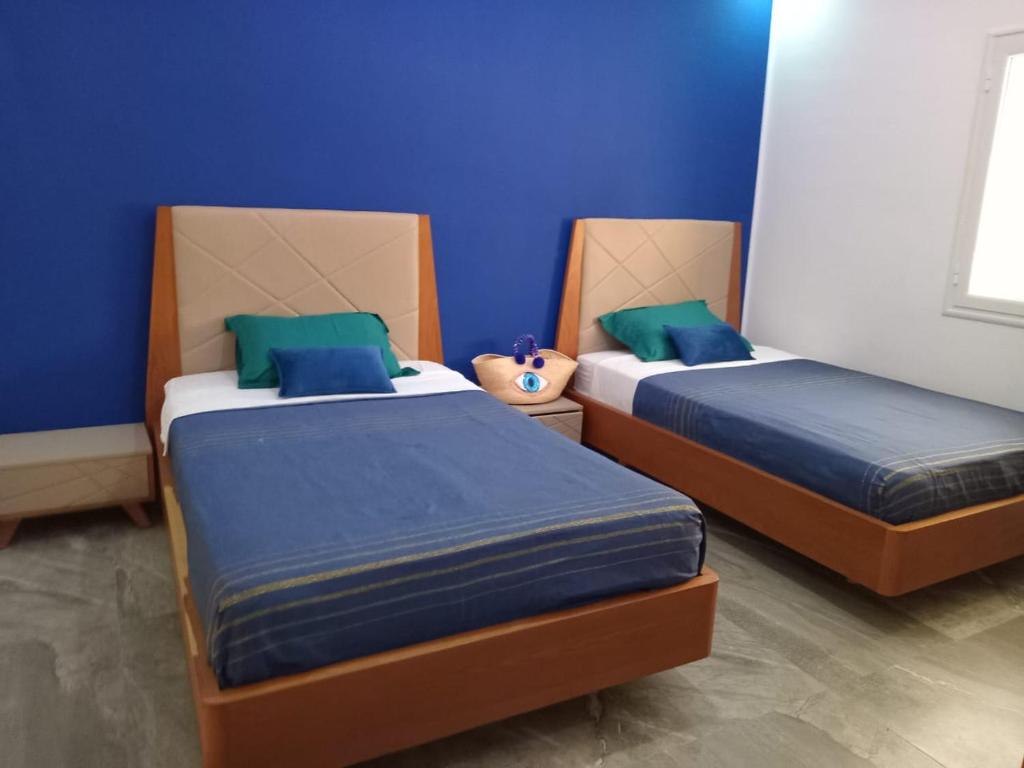 zwei Betten in einem Zimmer mit blauen Wänden in der Unterkunft Villa Majorelle à Tezdaine in Djerba