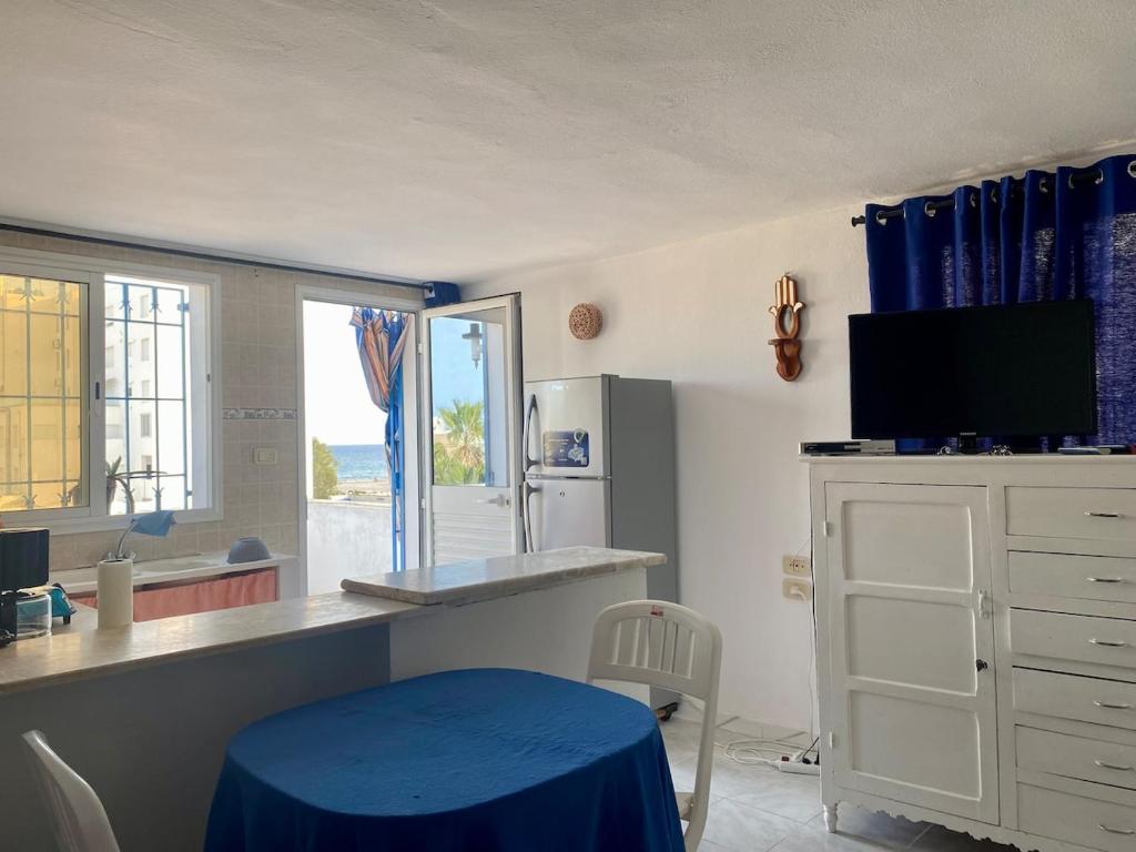 a kitchen with a blue table and a refrigerator at Charmant studio avec vue sur mer in Nabeul