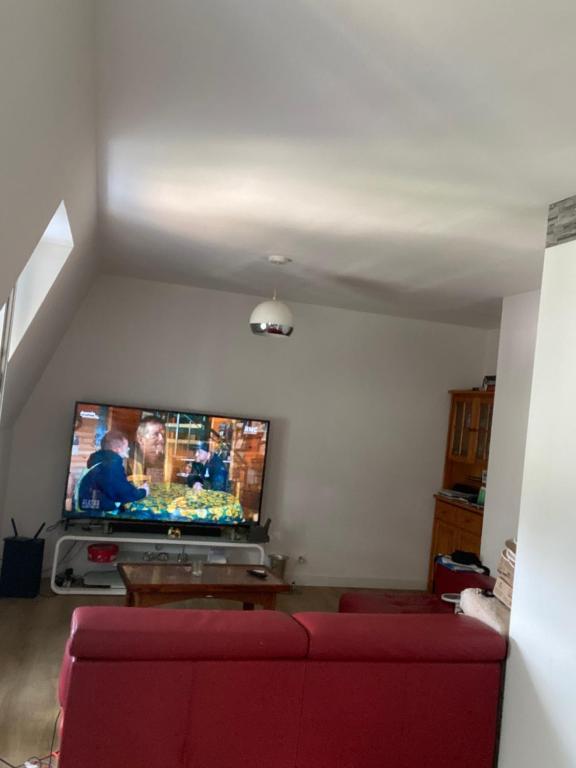 Una sala de estar con un sofá rojo y un televisor de pantalla plana. en Studio 30m2, en Thorigny-sur-Marne