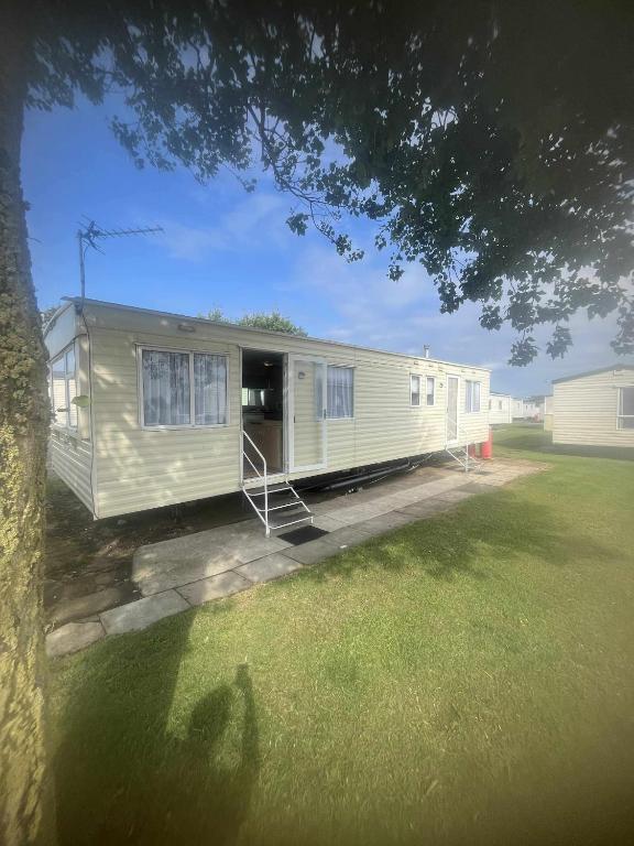 an rv parked in a yard with a tree at Seascape Holiday Caravan in Tunstall