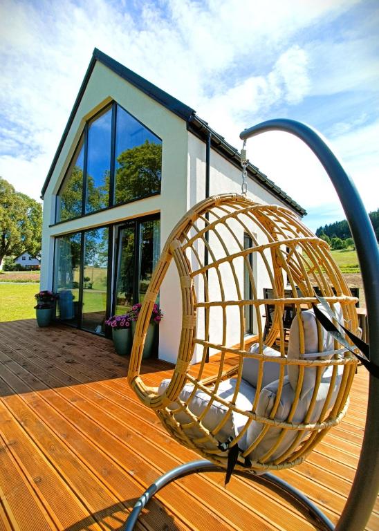 a rattan chair on a wooden deck with a house at Ptasi Śpiew in Grzędy