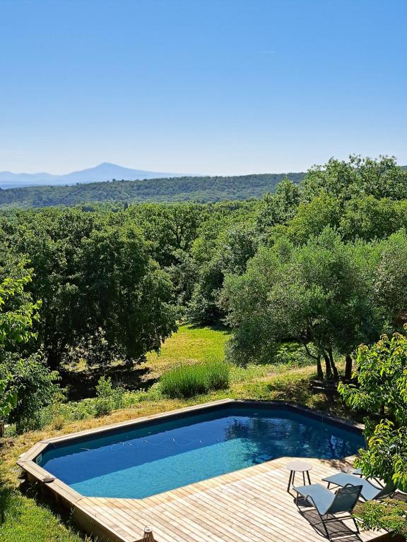 - une piscine avec une terrasse et une chaise dans l'établissement Le Chant des Tongs - La Canopée, à Salazac