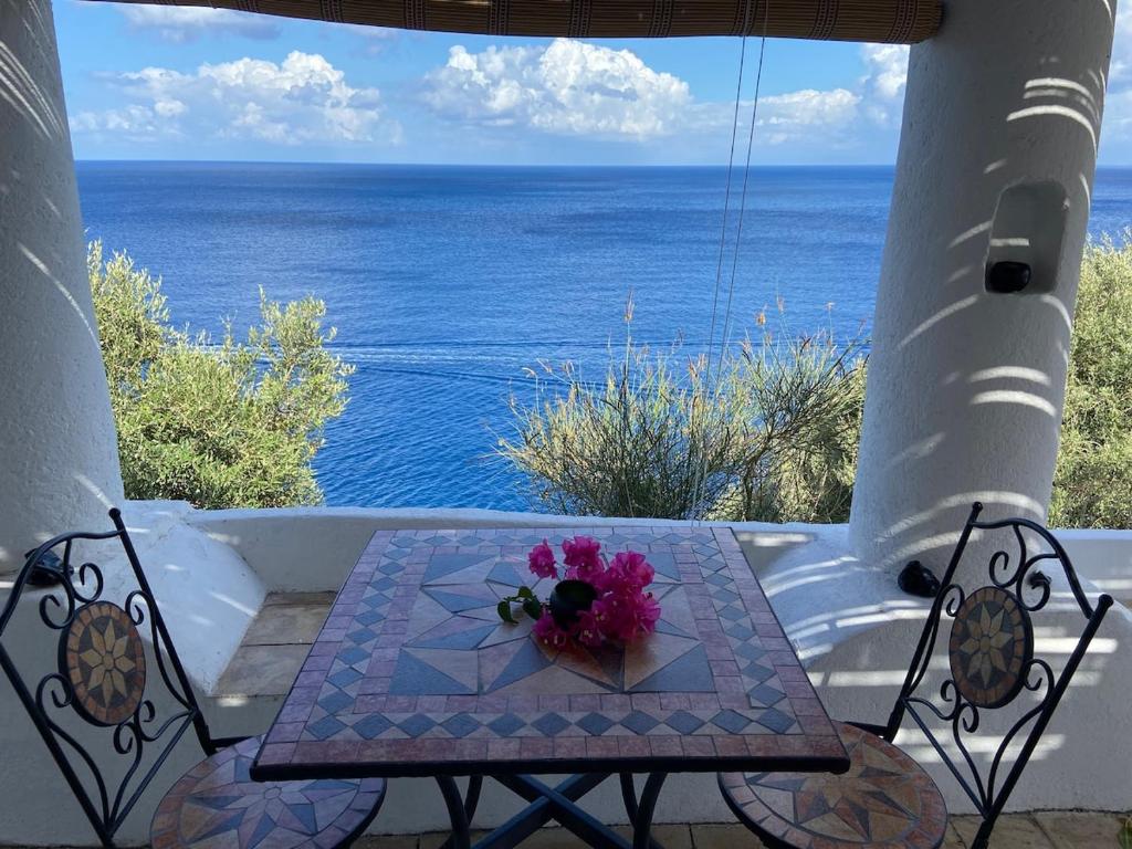 a table with a bouquet of flowers on a balcony at Traditional Eolian House Luna - Unique experience in San Salvatore