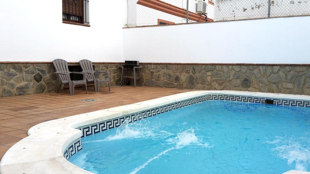 a large swimming pool with two chairs in a patio at Casa Miguel - El Bosque in El Bosque