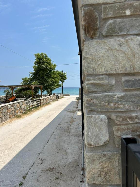 a stone wall next to a road next to the ocean at House Thomi in Skala Potamias