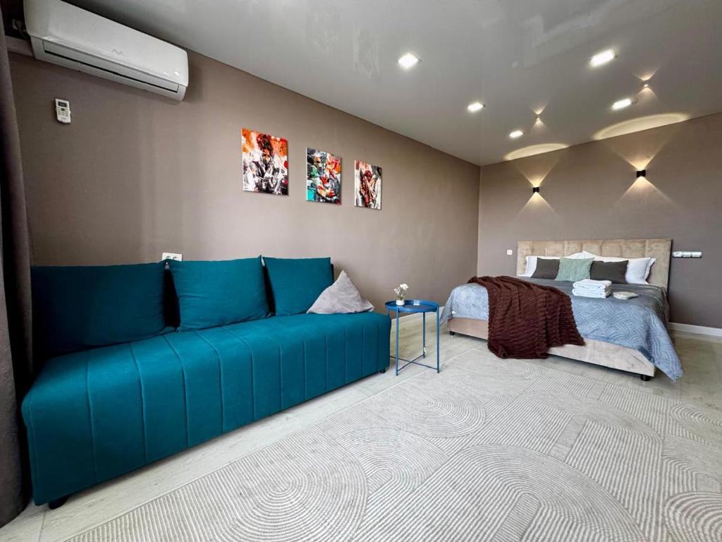 a living room with a blue couch and a bed at Квартира с видом на Усть-Каменогорск in Ustʼ-Kamenogorsk