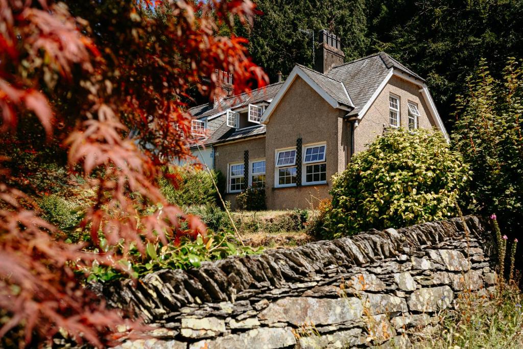 a house with a stone wall in front of it at Talfryn Cottages in Betws-y-coed