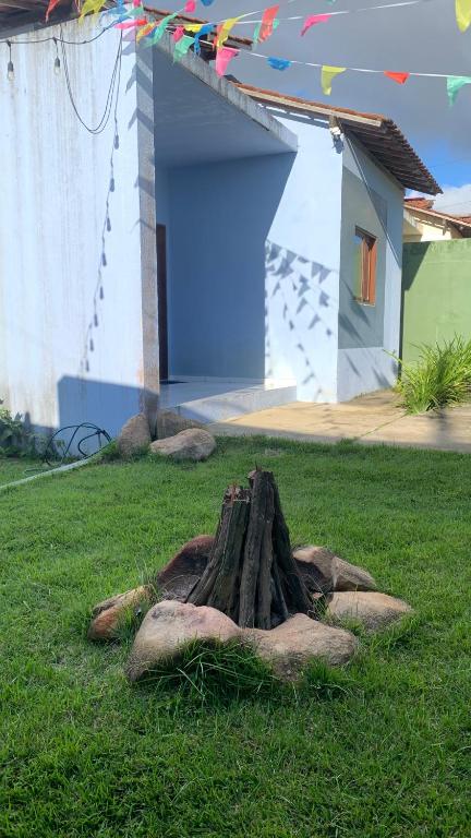 a tree stump in the grass in front of a house at Blue House Casa de temporada no brejo in Solânea