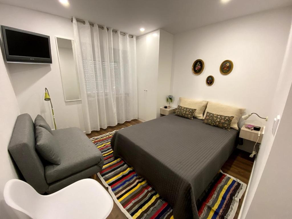 ein Schlafzimmer mit einem Bett, einer Couch und einem Sessel in der Unterkunft Casa da Covilhã - Pedra e Lã in Covilhã