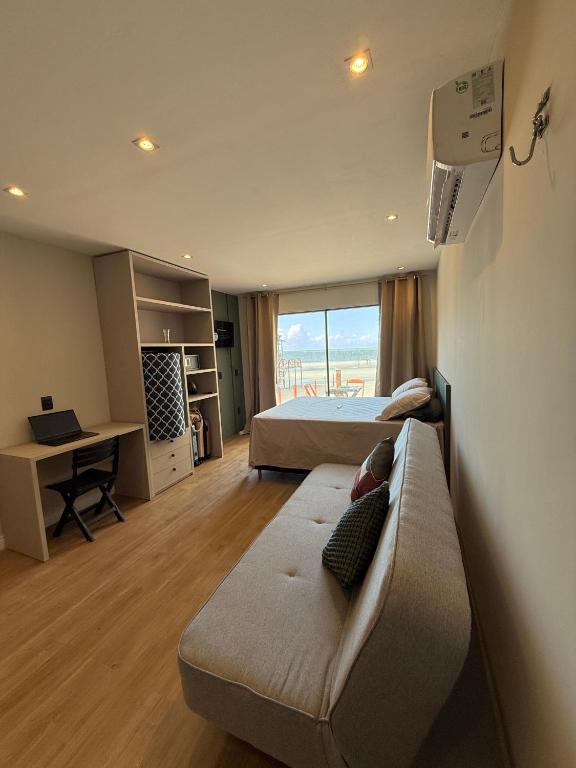a room with two beds and a couch and a desk at Nossos Chalés de Praia in Bragança