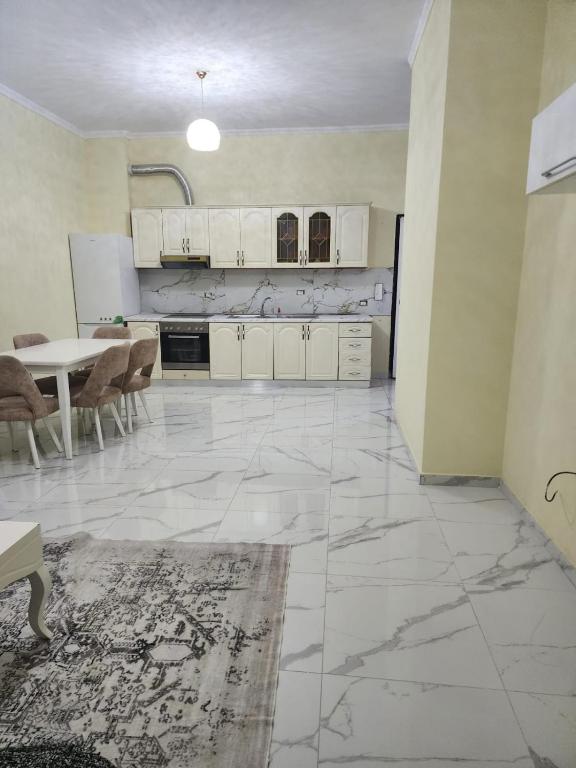 a large kitchen with white cabinets and a table at Kamez Albania in Kamëz
