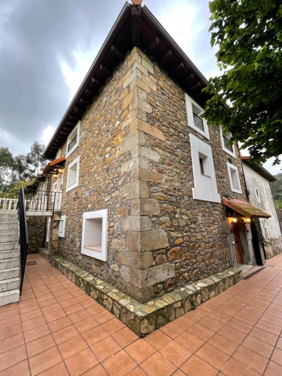 a stone building with white windows and a roof at Compuerta Otañes in Otañes