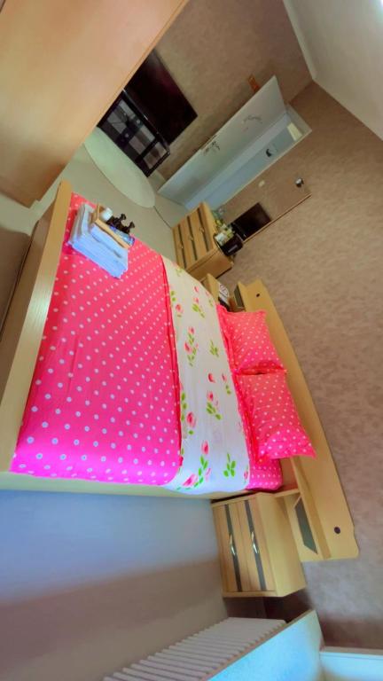 Una cama con almohadas rosas y blancas. en Gloryapartement, en Roeselare