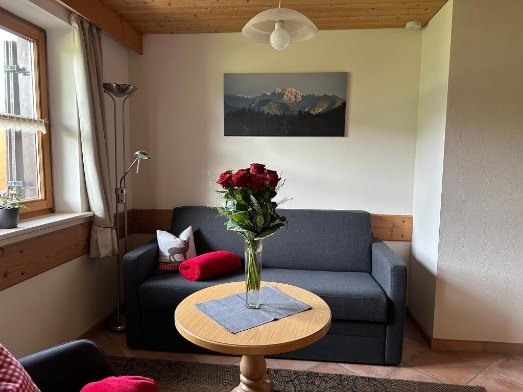 a living room with a couch and a vase of flowers on a table at Landhaus Brigitte in Obermaiselstein