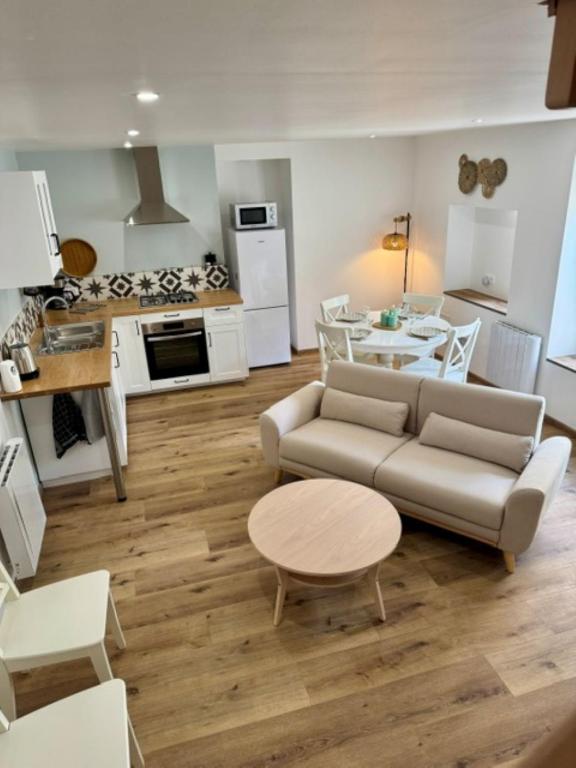a living room with a couch and a table and a kitchen at L'atelier du Vannier in Fayl-Billot