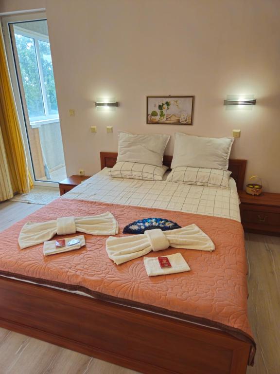 a bed with two towels and two dishes on it at Milushevi apartment in Golden Sands