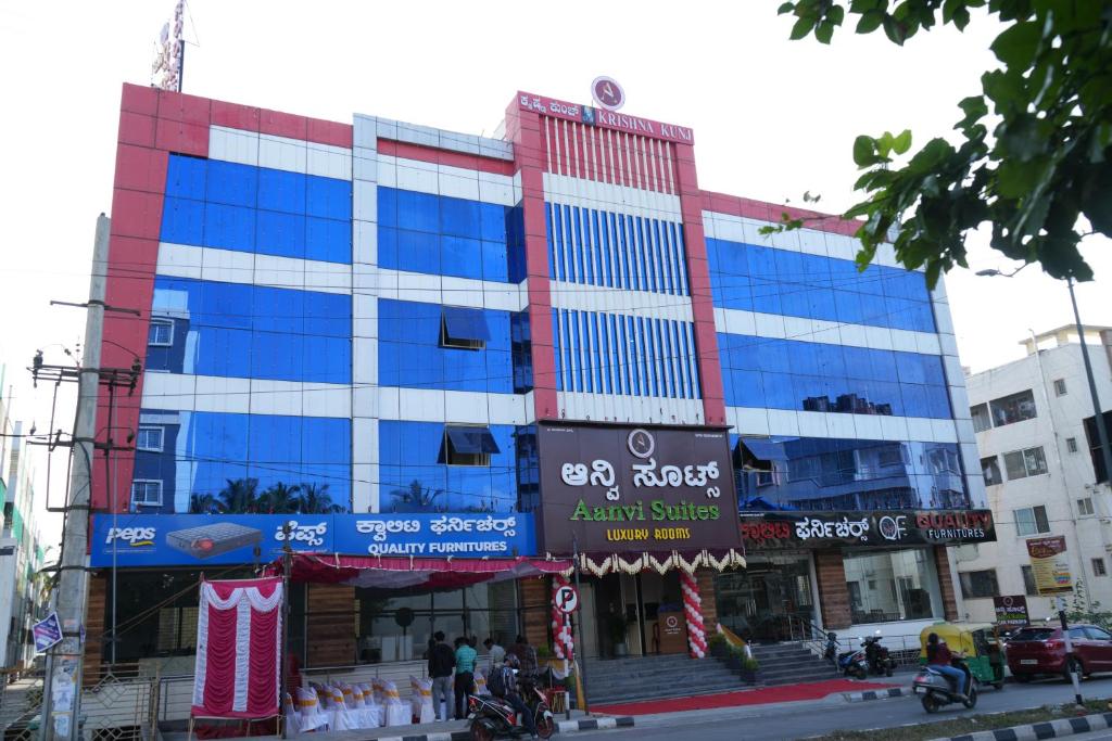 a large building with blue windows on a city street at Aanvi Suites RR nagar in Bangalore