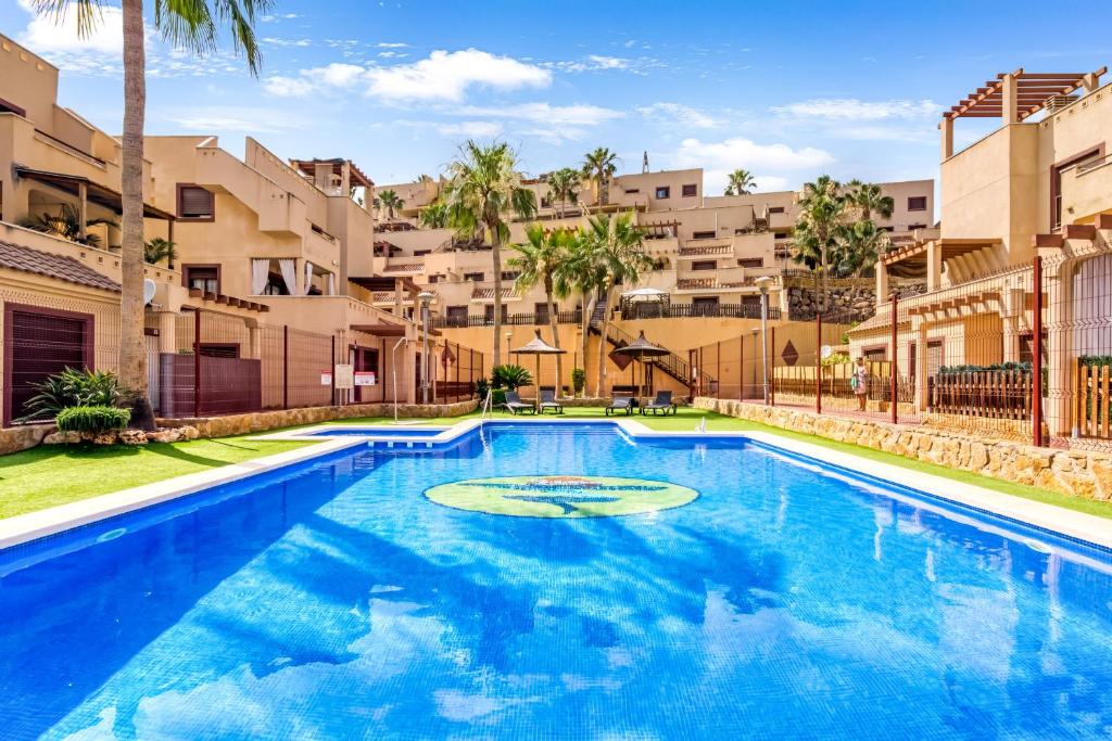 a swimming pool in front of some apartment buildings at Oasis in Los Collados - 2BR - Pool & Garden in Águilas