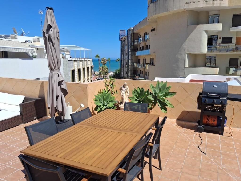 a wooden table and chairs and an umbrella on a patio at The Bajondillo terrace in Torremolinos