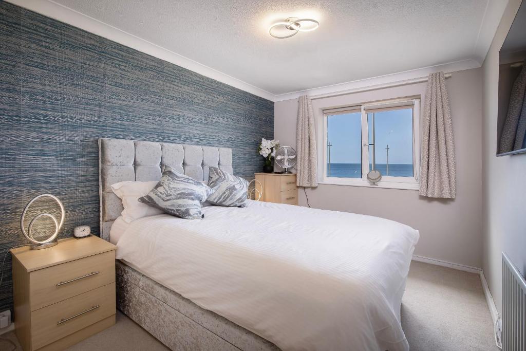 a bedroom with a large white bed with a window at The Beachcomber - seafront, free parking, free wifi in Cleveleys