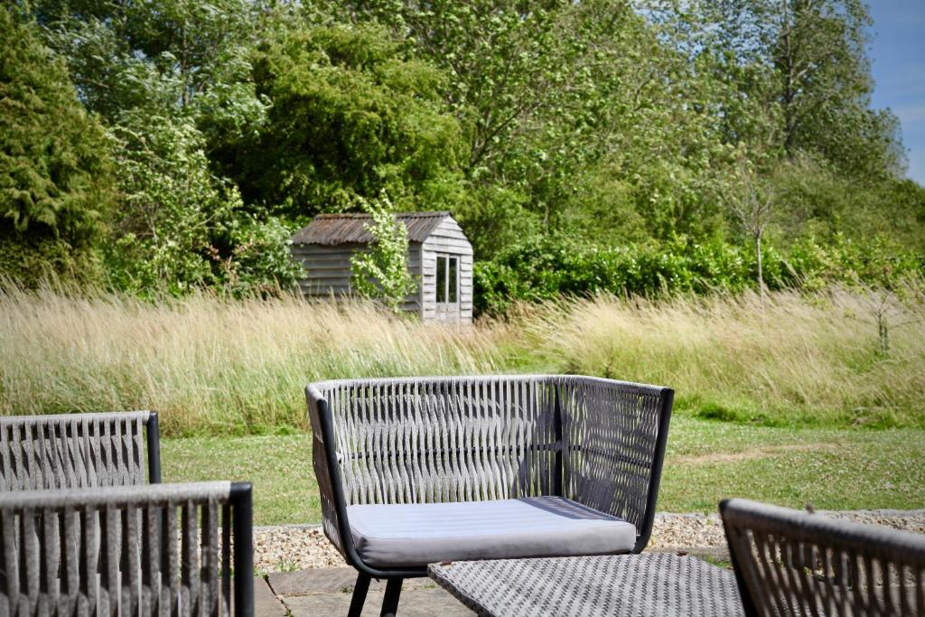 two chairs and a table with a bench and a shed at A Peaceful Cotswolds Retreat in Bourton on the Water