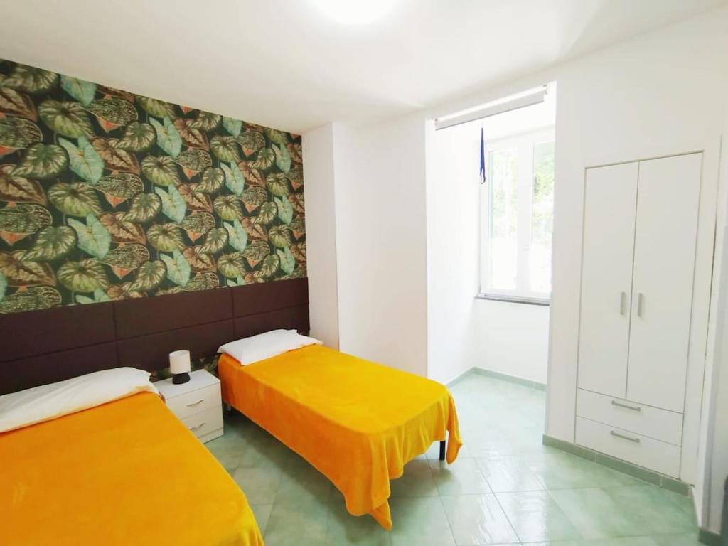 a bedroom with two beds with orange sheets at L'oblo' sul mare Sorrento Coast in Vico Equense