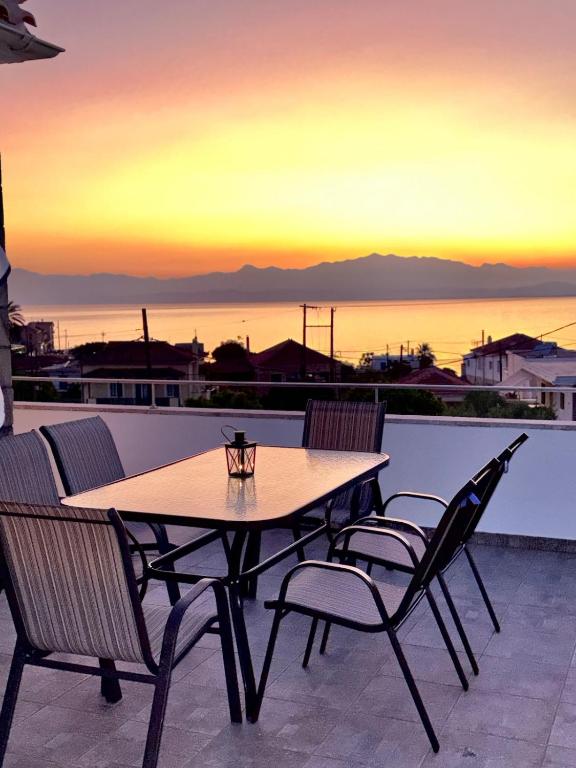 a table and chairs on a balcony with a sunset at 'Olea Luxury House in Elia Laconias
