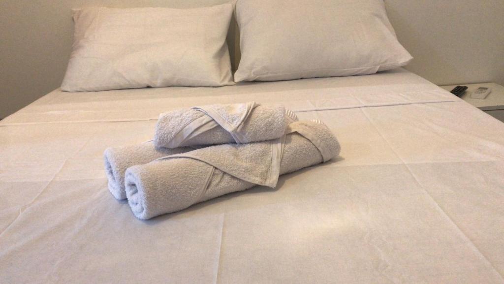 een stapel handdoeken bovenop een bed bij Santa Ana da Ribeira in SantʼAnna do Ipanema