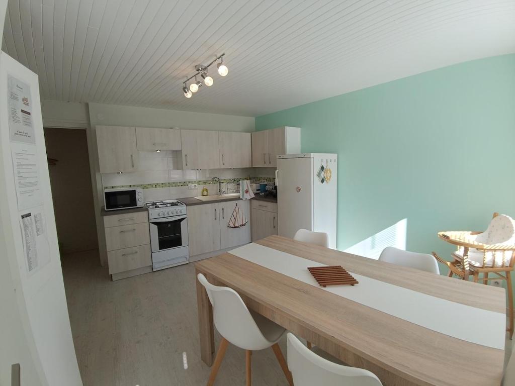 une cuisine avec une table en bois et des appareils électroménagers blancs dans l'établissement Charmante Maison de Village, à Riotord