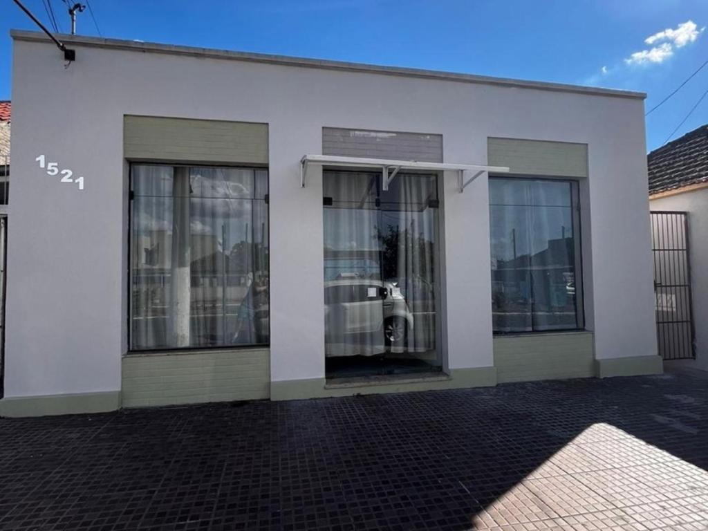 a white building with glass doors with a car in it at Pousada da Jô in São Gabriel