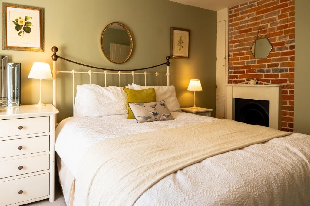 a bedroom with a white bed with a brick wall at Windlass Cottage in Lymington