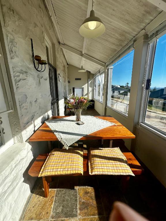 a table and benches in a room with windows at Corner Cottage on Hill in Mossel Bay
