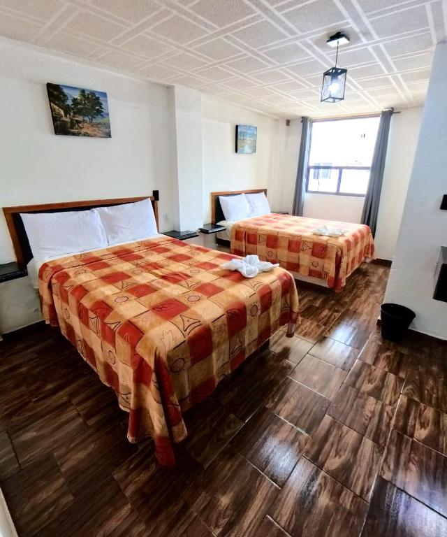 a hotel room with two beds and wooden floors at Palacio de los Angeles in San Felipe Hueyotlipan