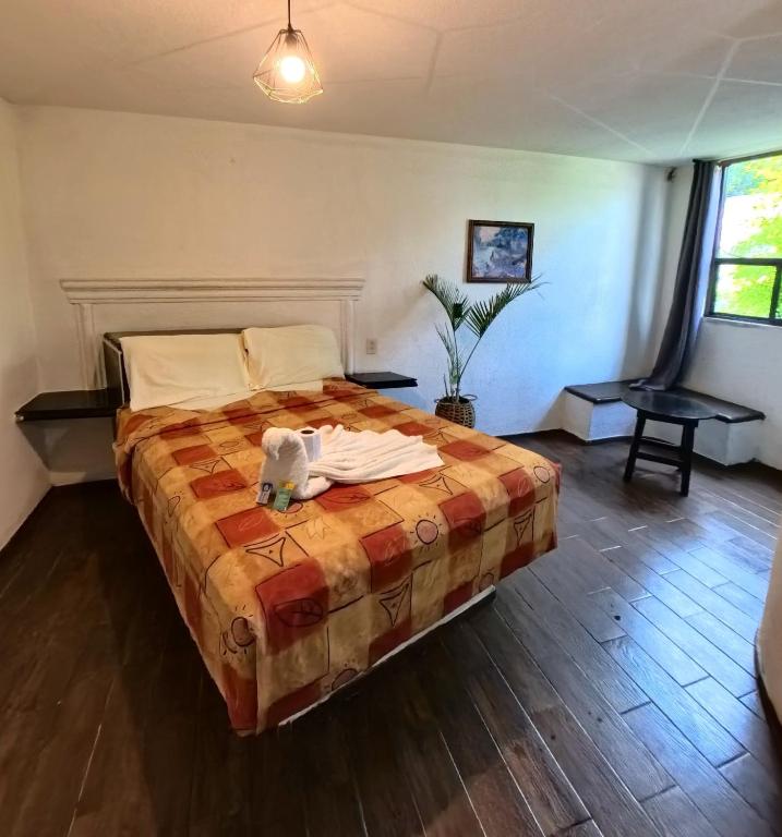 Un dormitorio con una cama con una manta encima. en Palacio de los Angeles, en San Felipe Hueyotlipan