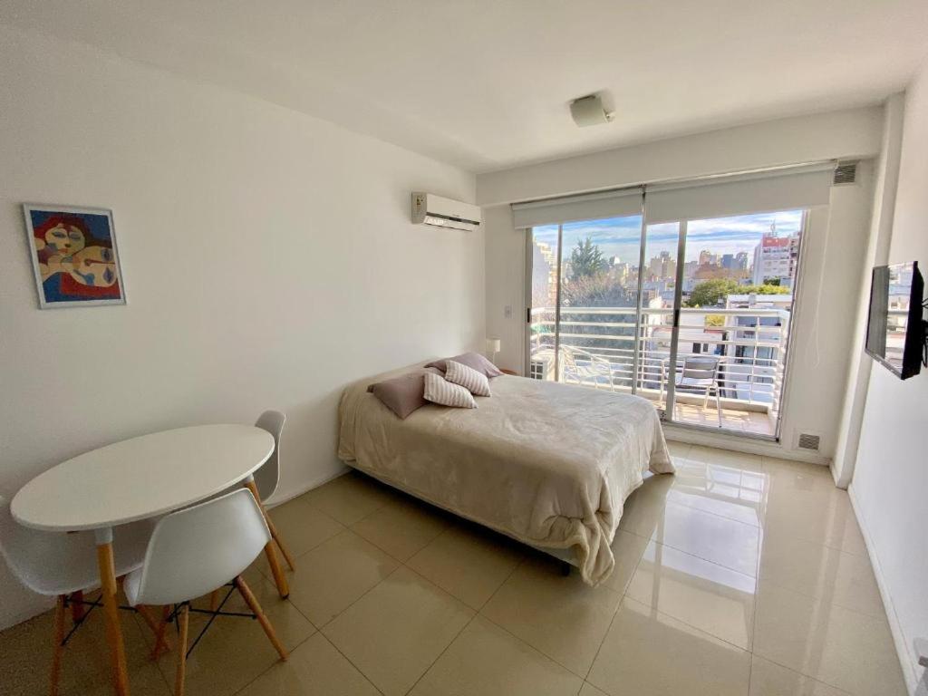 a bedroom with a bed and a table and a window at Palermo Soho Luxury Flat with pool and Amenities in Buenos Aires